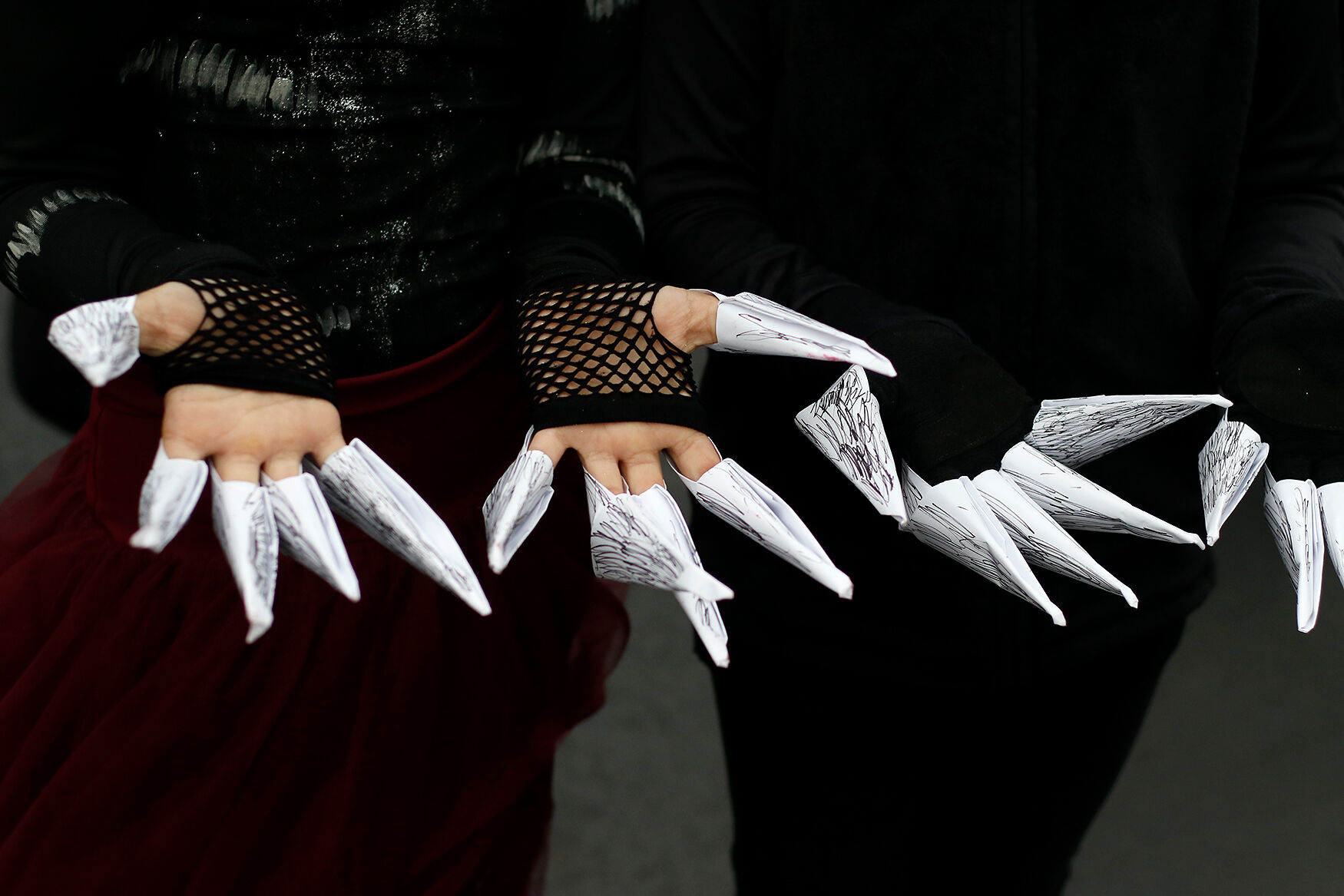 A pair of students show off their claws made of paper